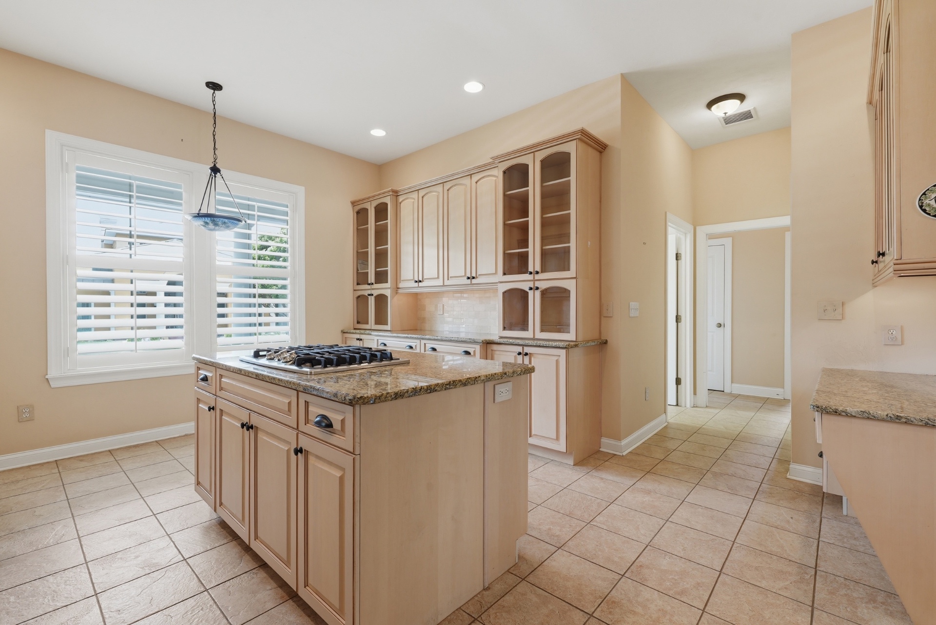 Kitchen with granite counters, custom cabinetry and gas cooktop island